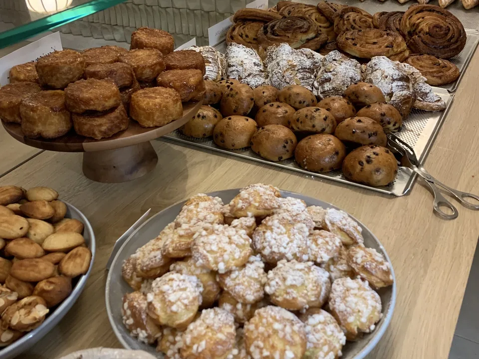 Le comptoir des viennoiseries : brioches, petits pains, roulés, chouquettes au sucre perlé et biscuits, sous la vitre.