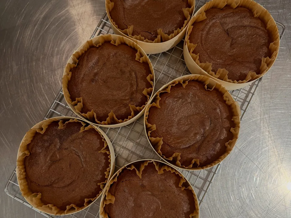 Six moelleux au chocolat dans leurs caissettes de papier, sur une grille.