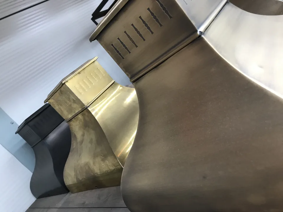 Trois pièces évasées en tôle ajourée, de même forme, en trois patines : noir, laiton vieilli et bronze.