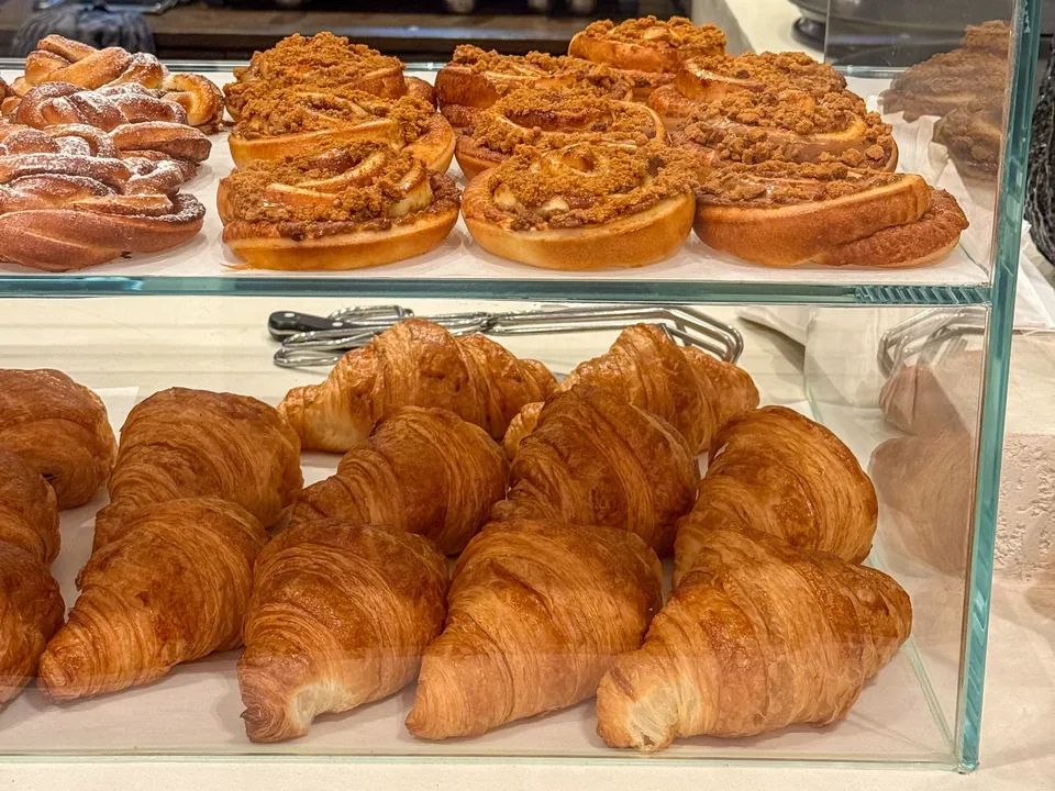 La vitrine de croissants et de rolls, avec l’inscription « Toutes nos gourmandises sont fournies par la Maison Ducobu ».