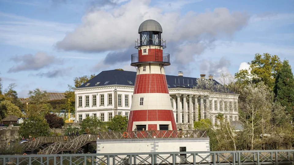 A red and white lighthouse in front of the castle that houses the aquarium, at Cambron-by-the-Sea.