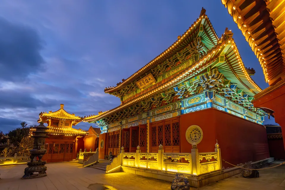 A Chinese temple with curved roofs, lit at dusk, in the Middle Kingdom.