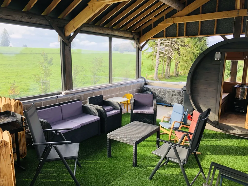 The covered terrace of Pegasus I: garden furniture, armchairs and the barrel sauna, overlooking the countryside.