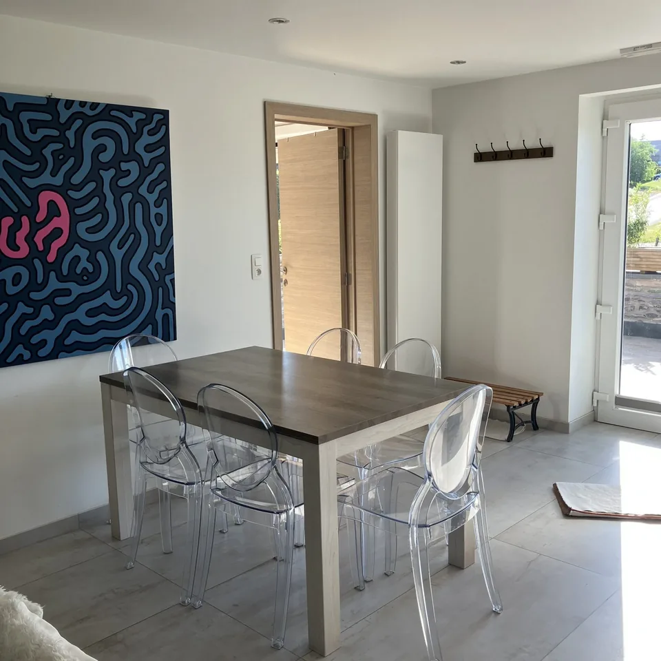 The dining area of Pegasus I: a table for six, transparent chairs and a large blue and pink painting.