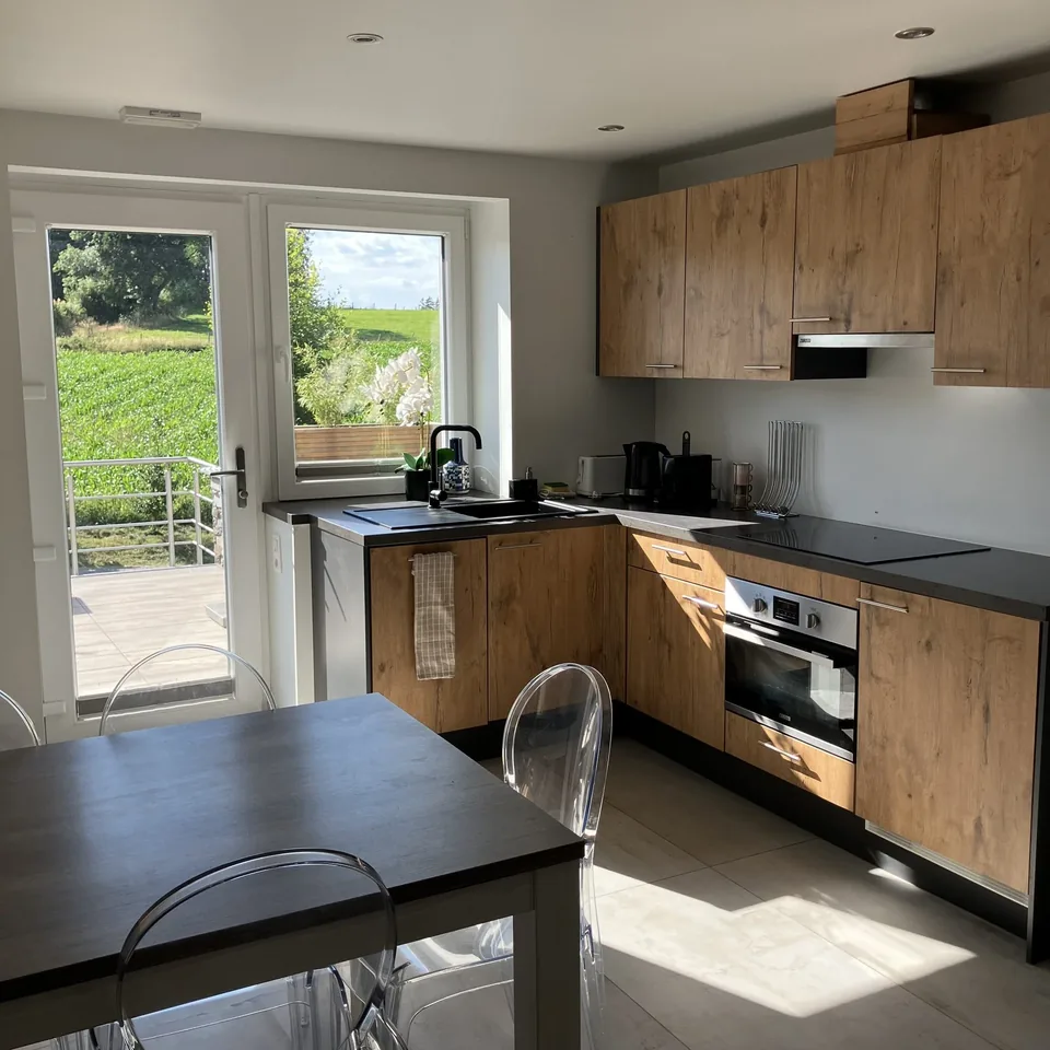 The fitted kitchen of Pegasus I, light wood with a black worktop, a glazed door onto the terrace.