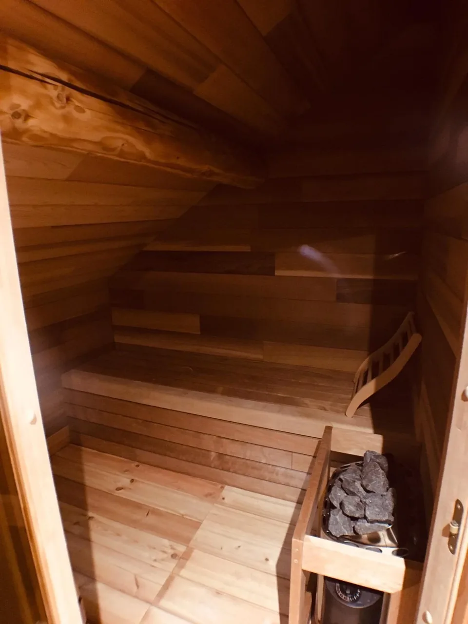 The Pegasus II sauna under the sloping roof, all wood, with its stone stove.
