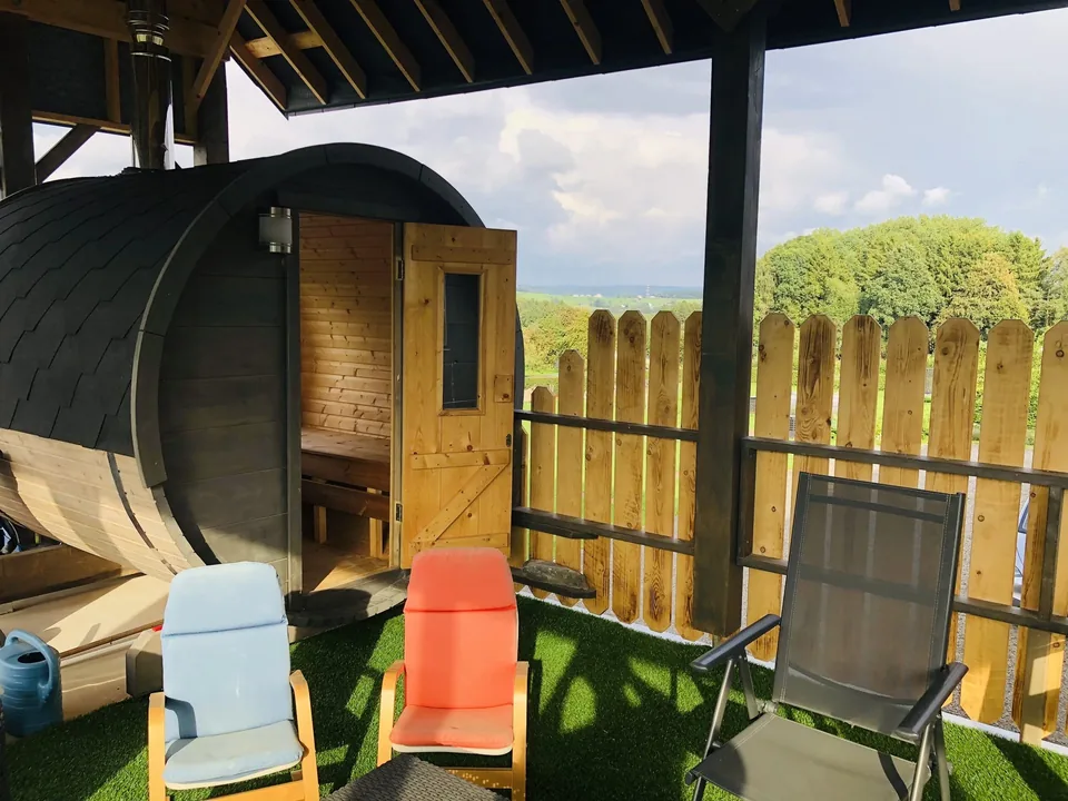 The barrel sauna of Pegasus I, door open, under the covered terrace, facing the meadows.