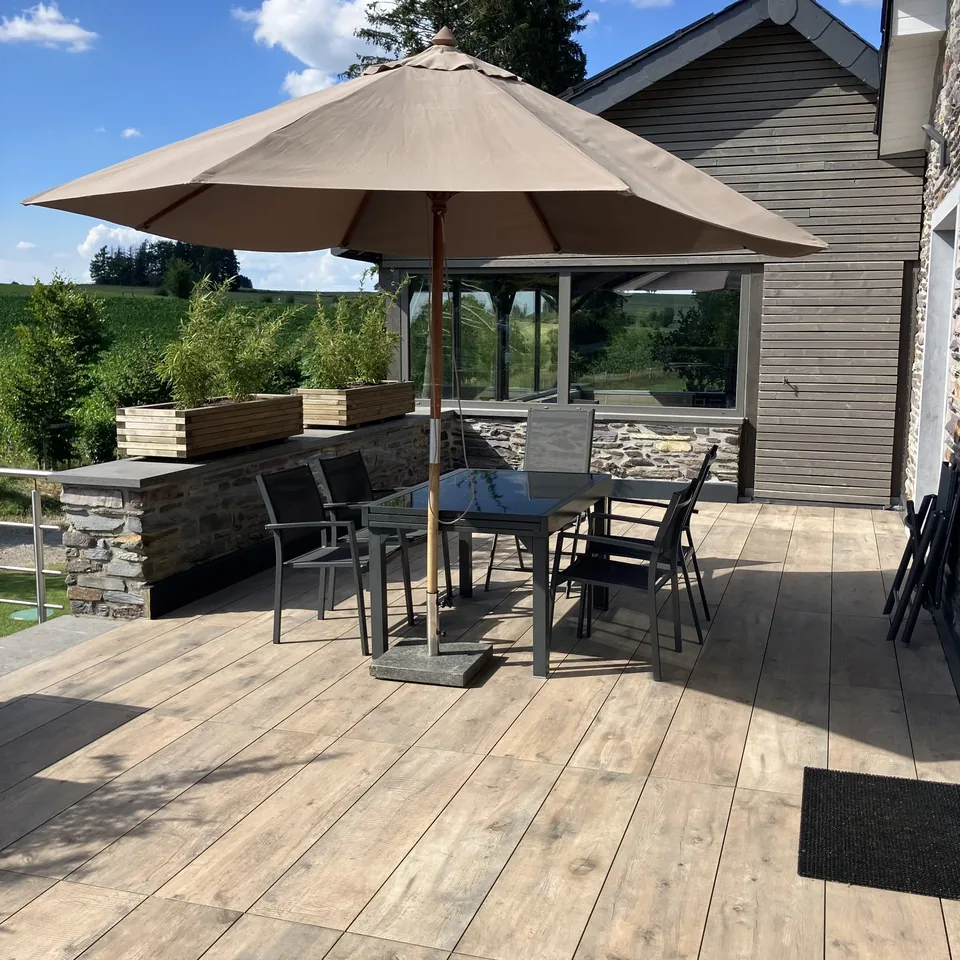 The large terrace: a table for six under a parasol, bamboo planters, fields in the distance.